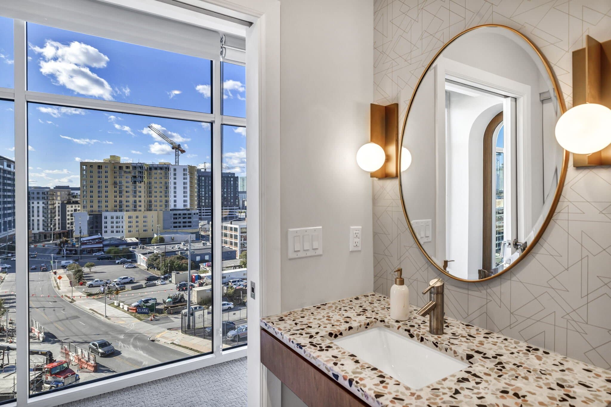 Bathroom at Haven at The Gulch with a terrazzo counter, brass fixtures, and a round mirror