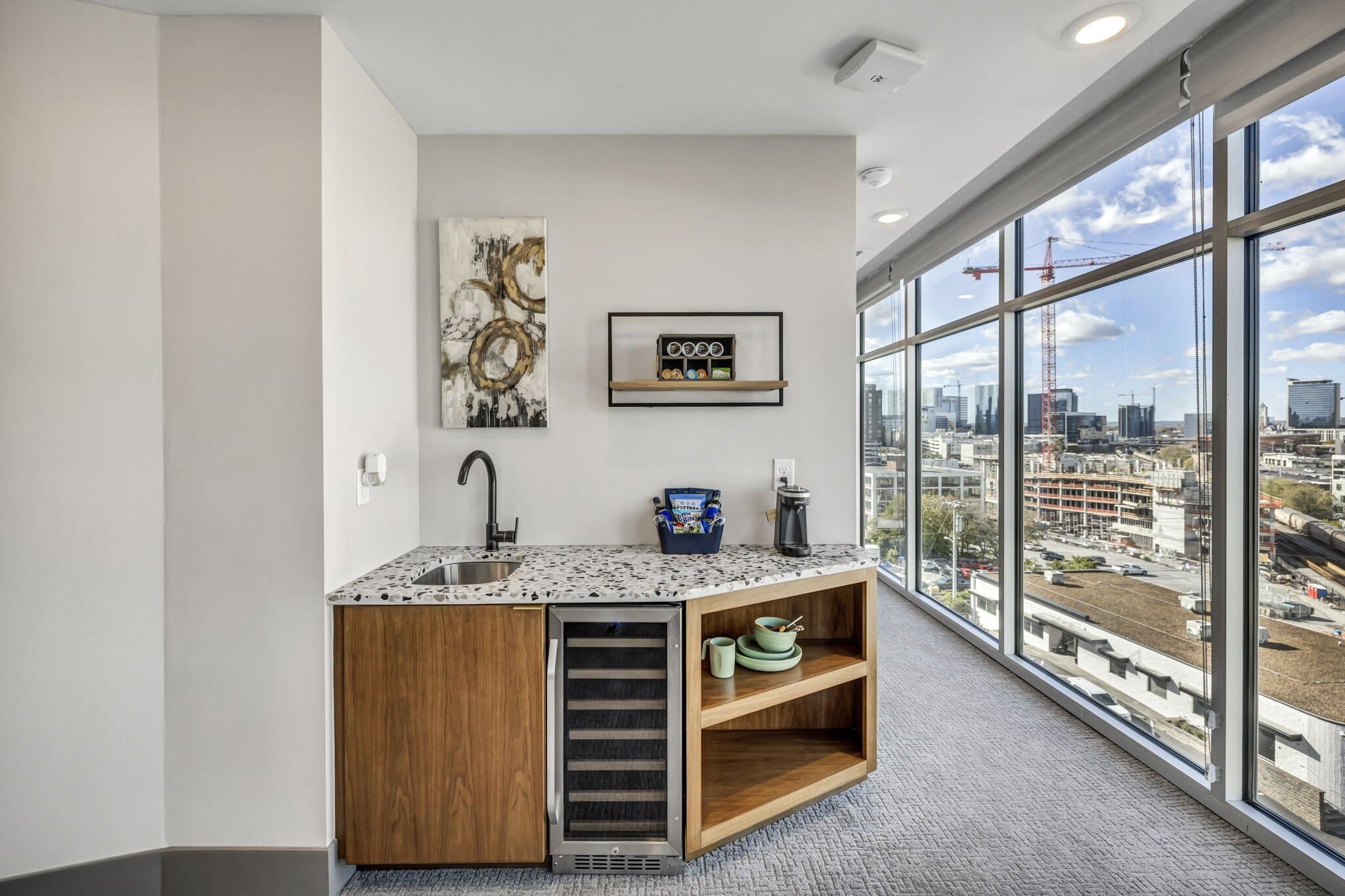 Kitchenette with a stone counter, wine fridge, and open shelving beside the windows